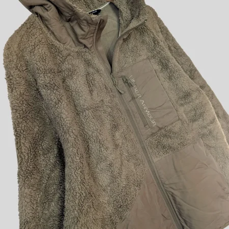 under-armour-fleece-material-nahaufnahme-flauschig Detailaufnahme der hochflorigen Sherpa-Fleece-Struktur für maximale Wärmeisolation.