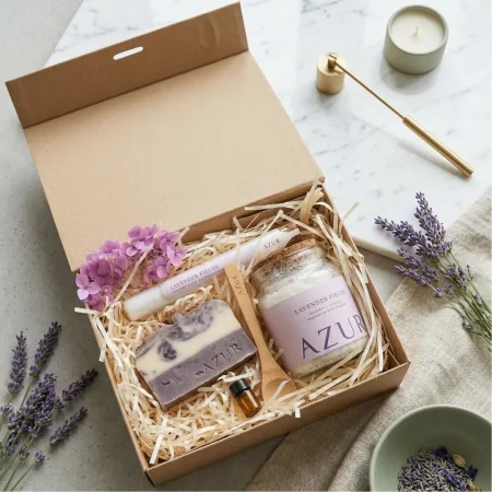 Wellness Geschenkset, luxuriöse dicke Karton-Geschenkbox mit Magnetverschluss des 'Lavender Fields' Wellness Geschenksets, gefüllt mit AZUR Seife, Magnesium-Badesalz-Glas, Tube, doTERRA Probe und Hydrangeablüten.