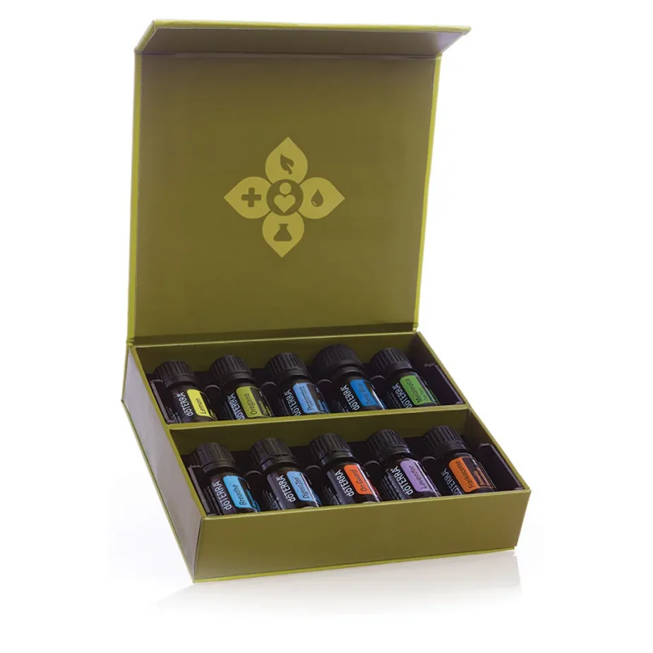 Ätherische Öle Starter-Set – doTERRA Family Essentials Kit (10-teilige Hausapotheke) Das geöffnete doTERRA Family Essentials Kit (ätherische Öle Starter-Set) auf einem rustikalen Vintage-Holztisch, das die 10 sortierten Ölfläschchen in ihren Fächern und das goldene Logo im Deckel zeigt, freigestellt.