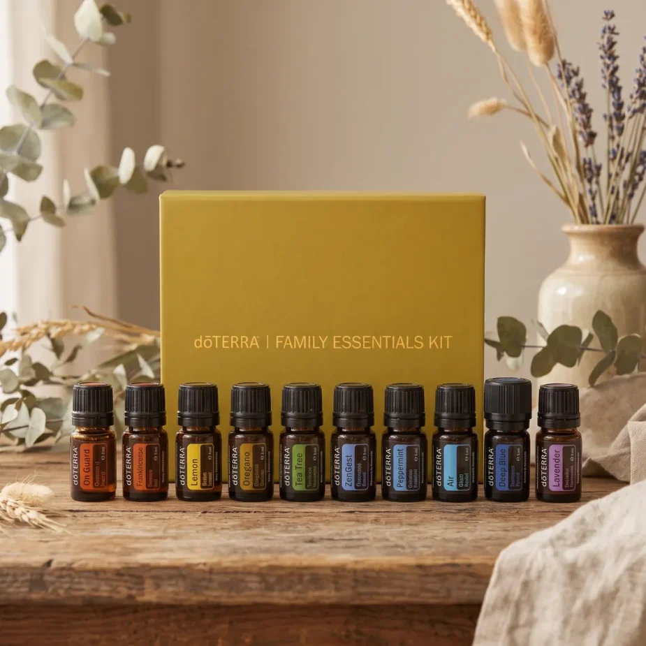 Ätherische Öle Starter-Set – doTERRA Family Essentials Kit (10-teilige Hausapotheke) Das geschlossene doTERRA Family Essentials Kit (ätherische Öle Starter-Set) mit den 10 kleinen 5ml-Fläschchen davor auf einem rustikalen Holztisch mit natürlicher Vintage-Deko wie Eukalyptus und Trockenblumen.